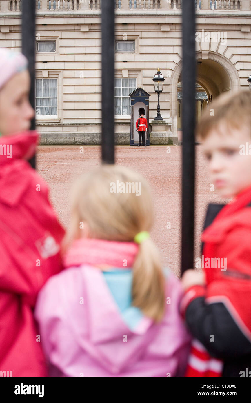 Kinder sehen ein Soldat in einem Bärenfell Hut auf Wachablösung am Buckingham Palace. Stockfoto
