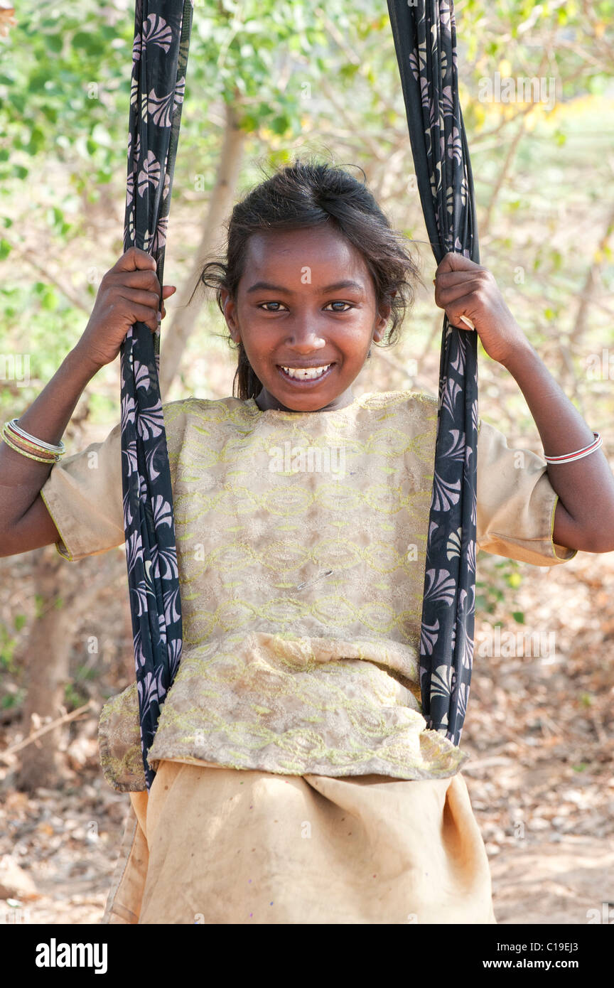 Glückliches armes niedrigeres Kaste indischen Straße Mädchen lächelnd saß in einem Sari-Schwung. Andhra Pradesh, Indien Stockfoto