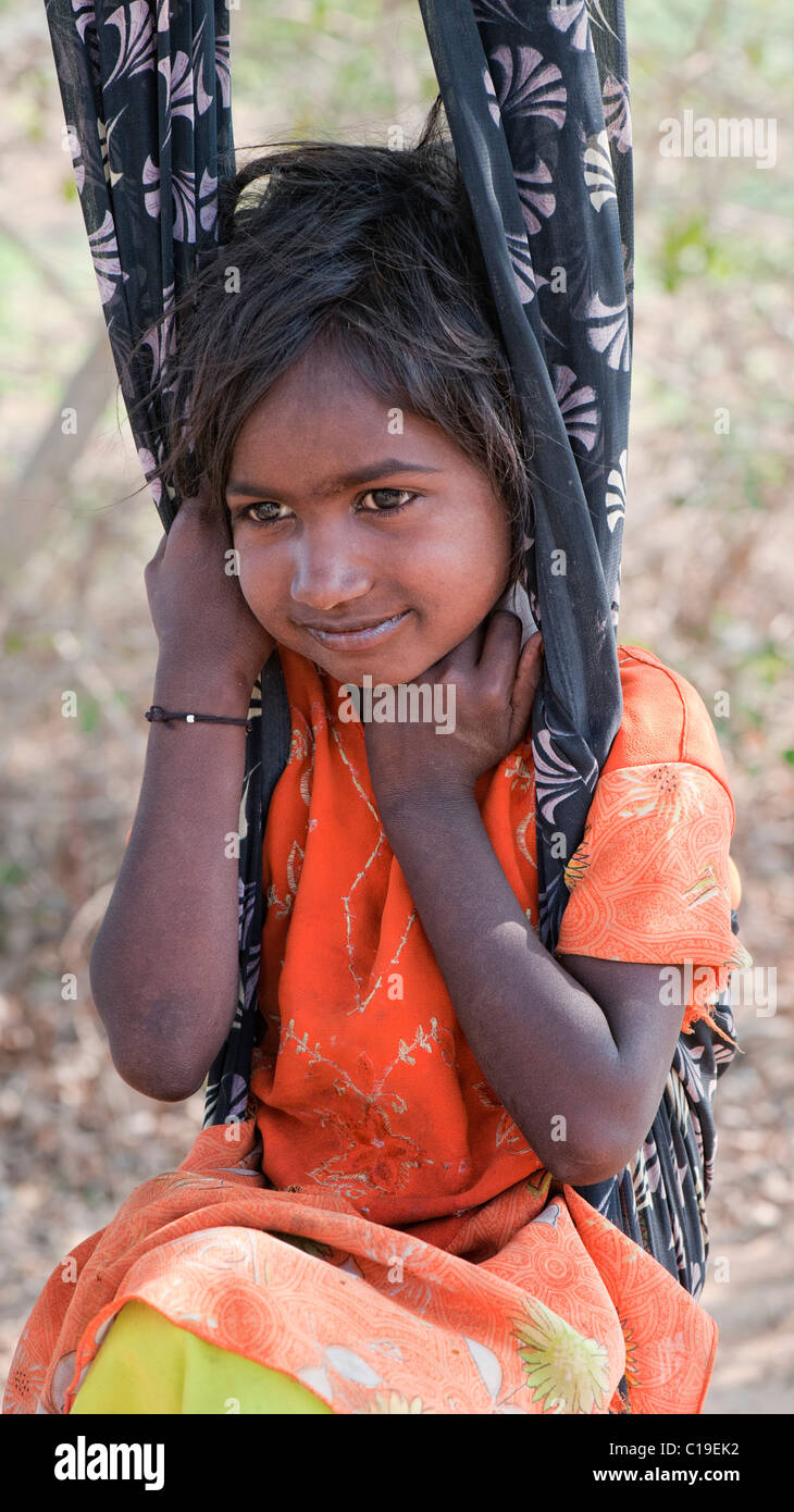 Glücklich Arm niedriger Kaste indischen Straße Mädchen Tagträumen saß in einem Sari-Schwung. Andhra Pradesh, Indien Stockfoto