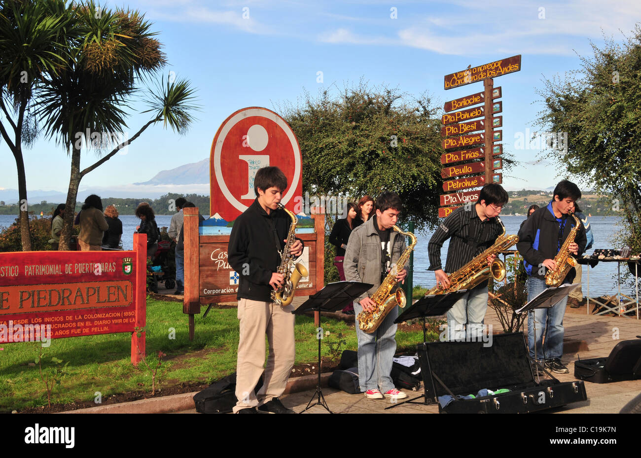 Blauer Himmel Abend Blick auf vier Jugendliche spielen Saxophone auf einem grasbewachsenen Pflaster an der Seite von See Llanquihue, Puerto Varas, Chile Stockfoto