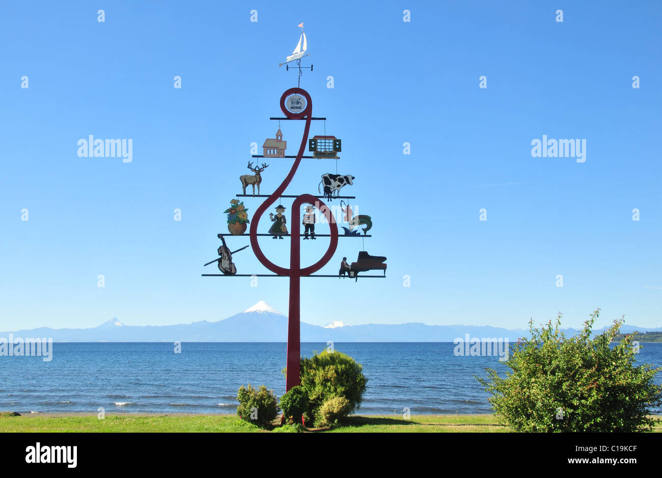 Blauer Himmel mit Blick auf eine hoch Musikfestival Hinweis Schriftzug auf einer grünen See Llanquihue Uferpromenade in Richtung Volcan Osorno, Frutillar, Chile Stockfoto