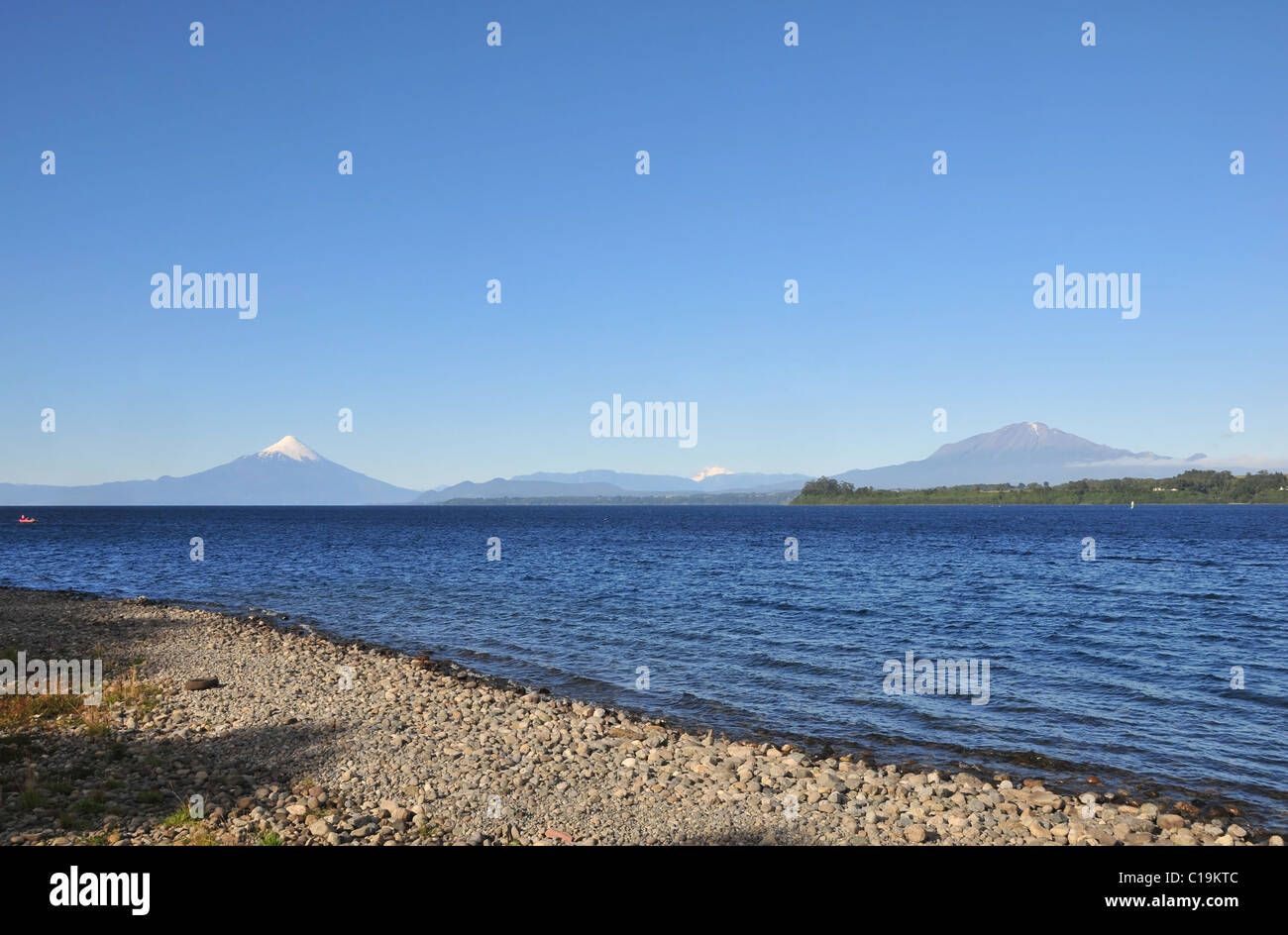 Blauer Himmel-Strand-Blick auf das Wasser des Llanquihue Sees, mit Blick auf den Osorno und Calbuco Vulkane, Puerto Varas, Chile Stockfoto