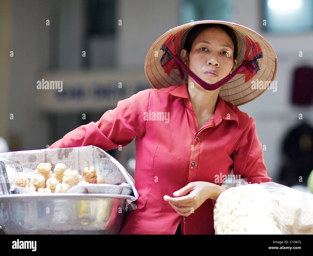 Eine Vietnamesin in ihrem traditionellen Non La Hut verkauft frische Lebensmittel auf den Straßen von Hanoi, Vietnam Stockfoto