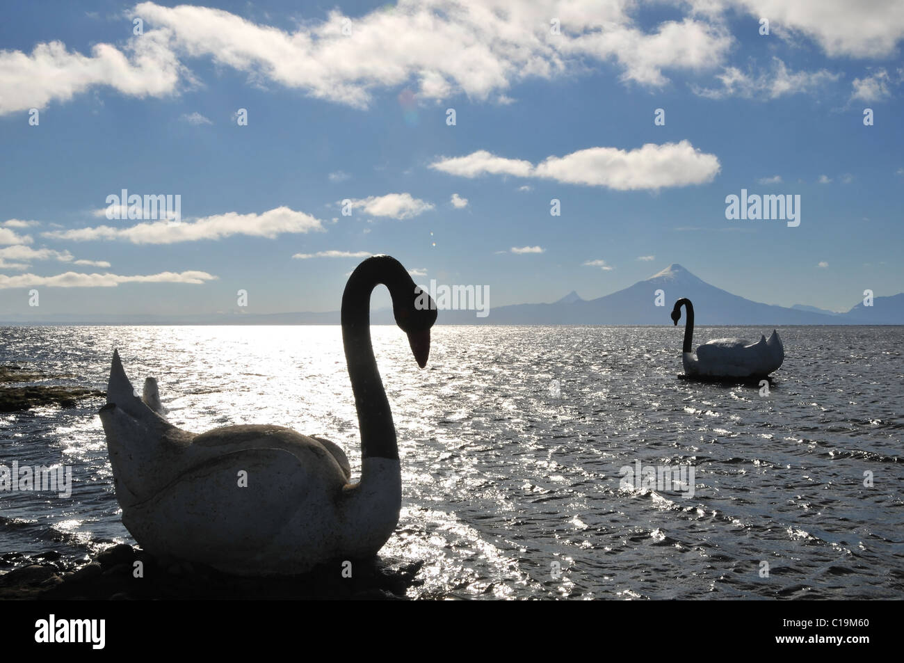 Blauer Himmel Silhouette Blick Volcan Osorno, zwei große künstliche Schwäne am glitzernden Wasser des See Llanquihue, Chile Stockfoto