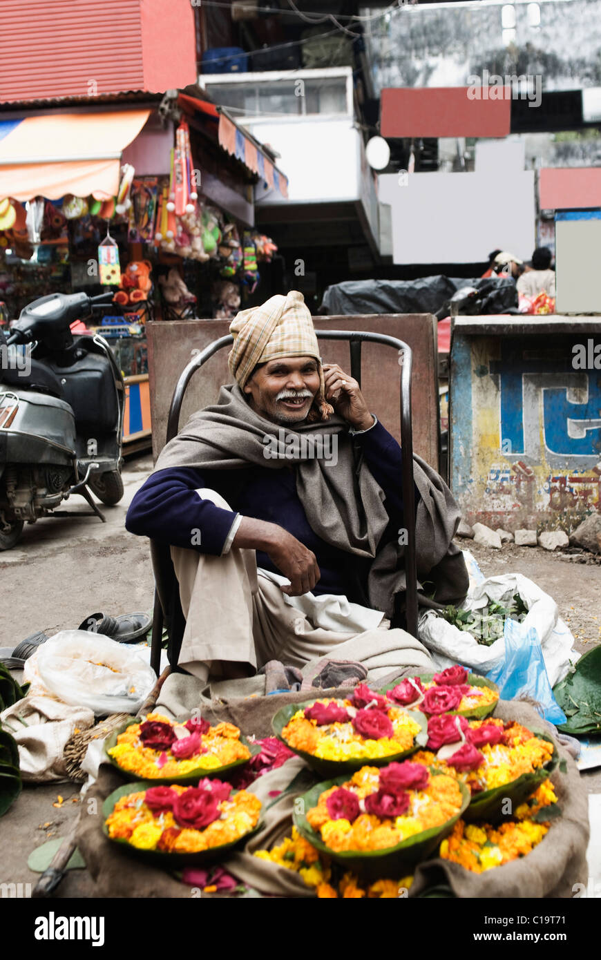 Anbieter verkaufen Blumen und telefonieren mit einem Handy, Haridwar, Uttarakhand, Indien Stockfoto
