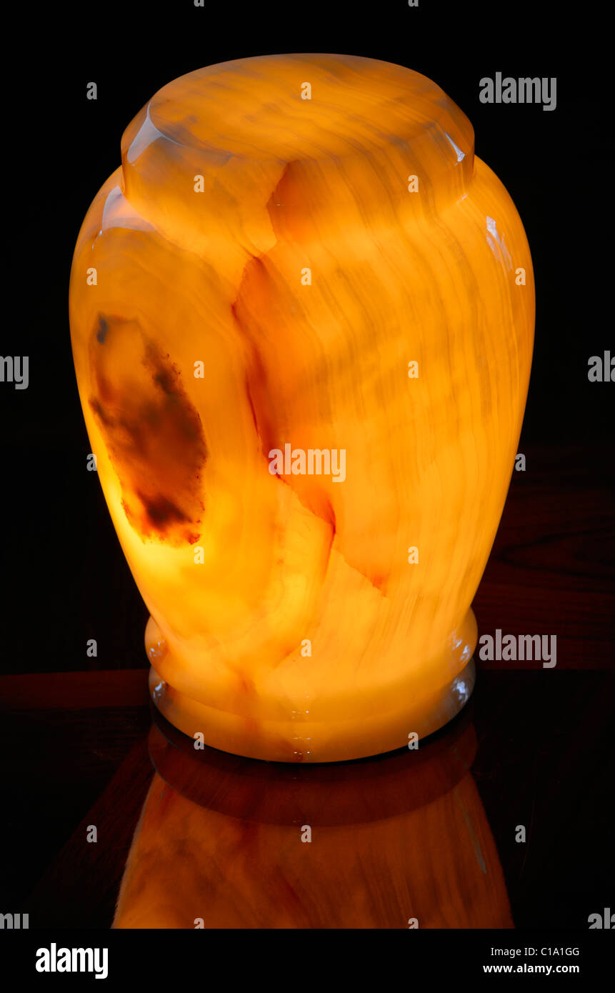 Gebänderte onyx mineral Einäscherung urn orange leuchtende mit einer inneren Licht auf einen hölzernen Tisch Stockfoto