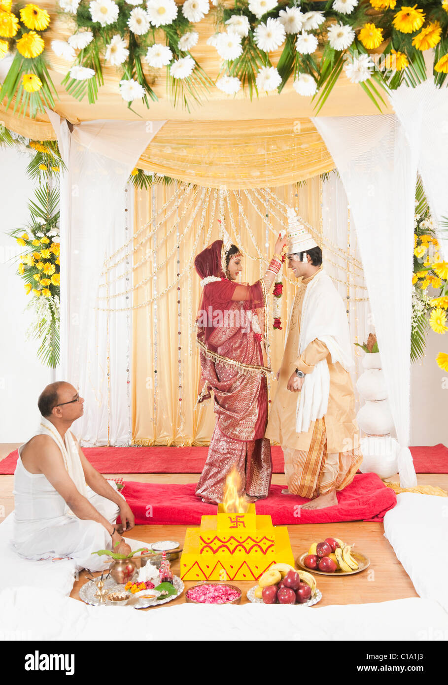 Durchführung von Mala Badal (Austausch von Garland) Zeremonie in Bengali Hochzeit paar Stockfoto