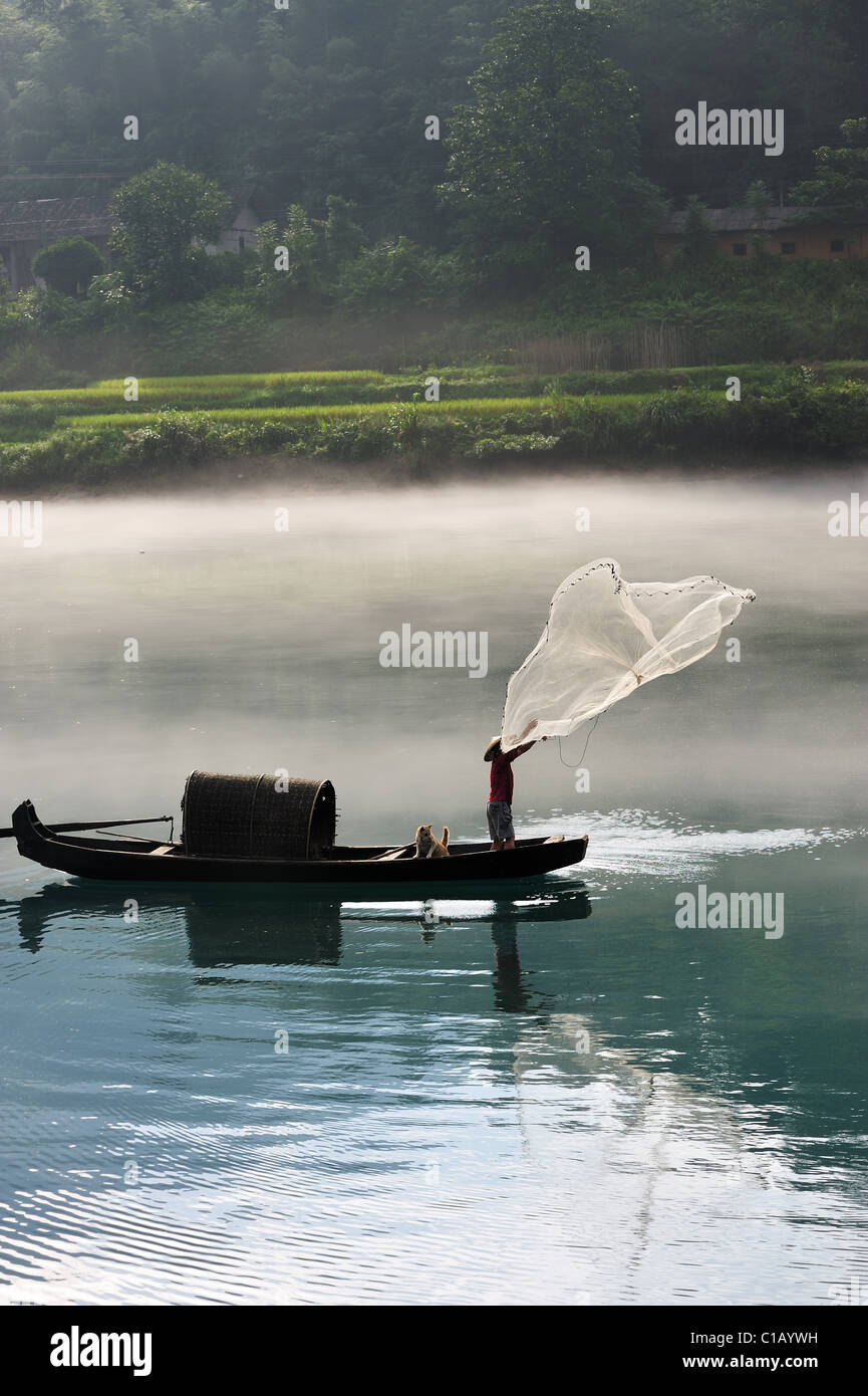 Ein Fischer wirft sein Netz aus dem Boot auf dem Fluss
