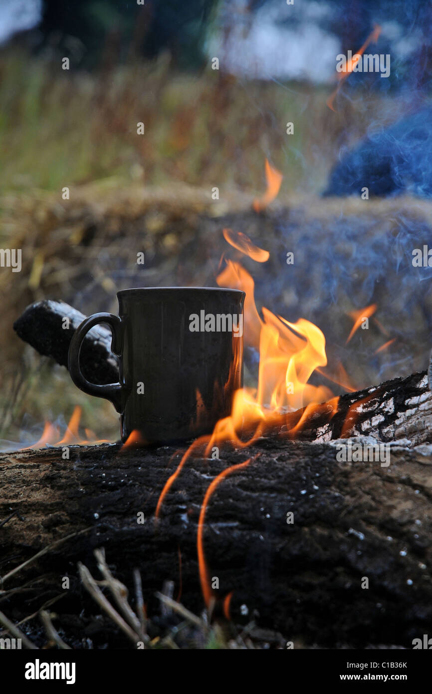 Eine Tasse Tee oder Kaffee aufwärmen über dem offenen Feuer während im Camp. Stockfoto