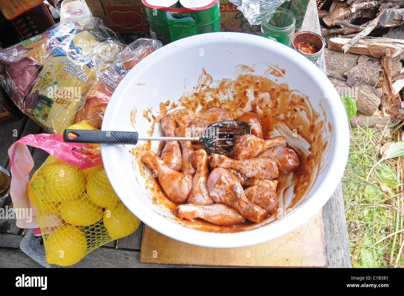 Outdoor-Kochen und Essen im Freien. Hähnchenschenkel mariniert wird in Bbq-Sauce bereit zu gehen auf dem offenen Feuer auf einem Campingplatz. Stockfoto