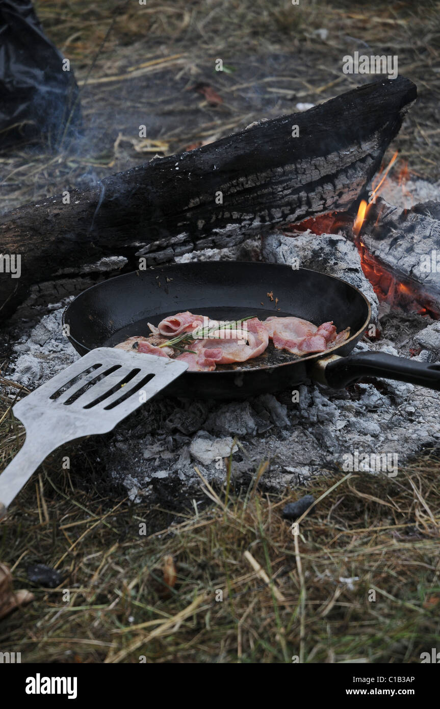 Kochen Speck zum Frühstück am offenen Feuer auf dem Campingplatz. Stockfoto