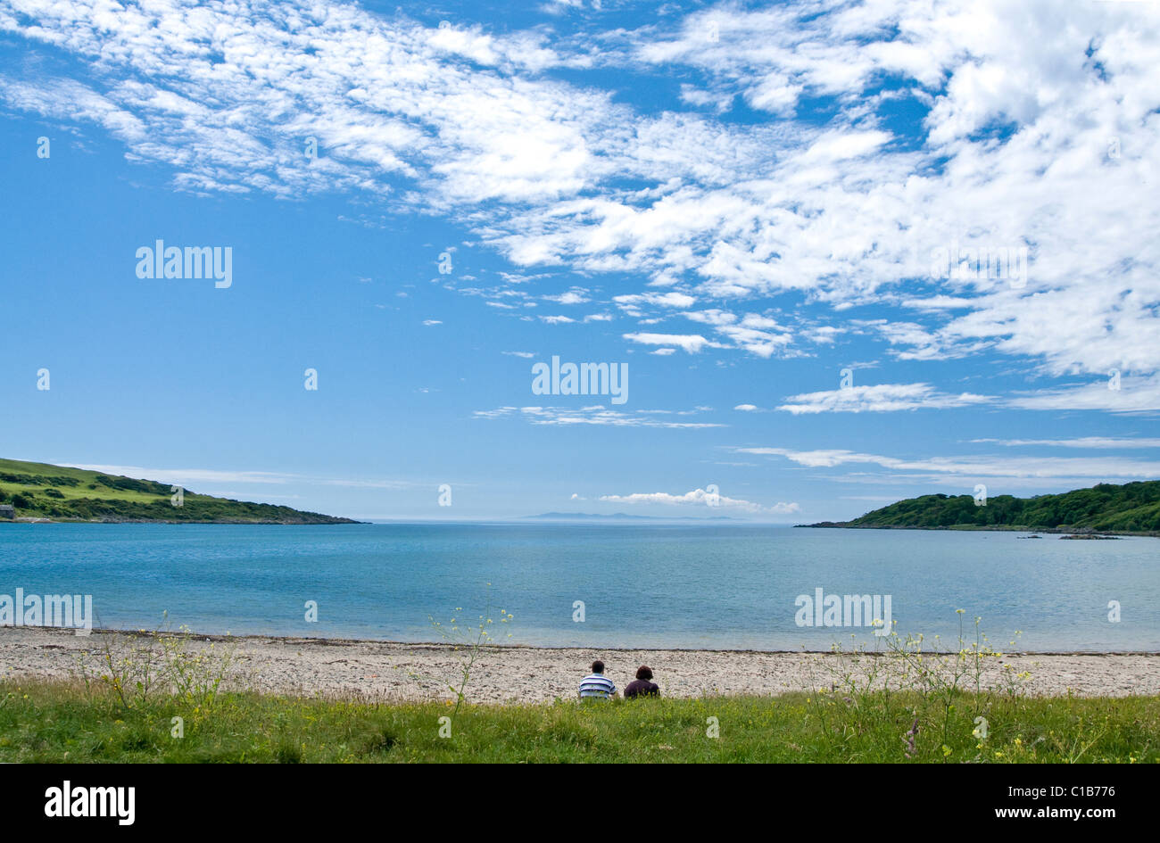Mittleren gealterten paar meditieren auf einem einsamen Strand mit großen blauen Himmel, Brighouse Bay, Galloway Stockfoto