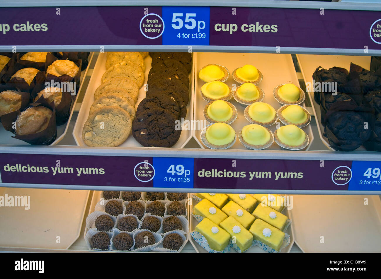 Auswahl an ungesunden Kuchen auf dem Display im schottischen High Street-Bäckerei-Fenster Stockfoto