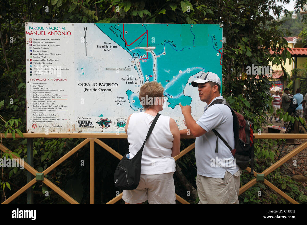 Ein Führer spricht mit einem Touristen vor eine Karte am Eingang nach Manuel Antonio Nationalpark, Costa Rica Stockfoto