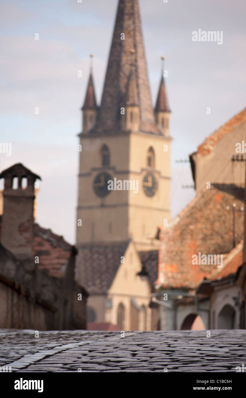 Kirchturm in Sibiu Rumänien unscharf, mit Schwerpunkt auf dem Kopfsteinpflaster Steinpflaster Straße Stockfoto