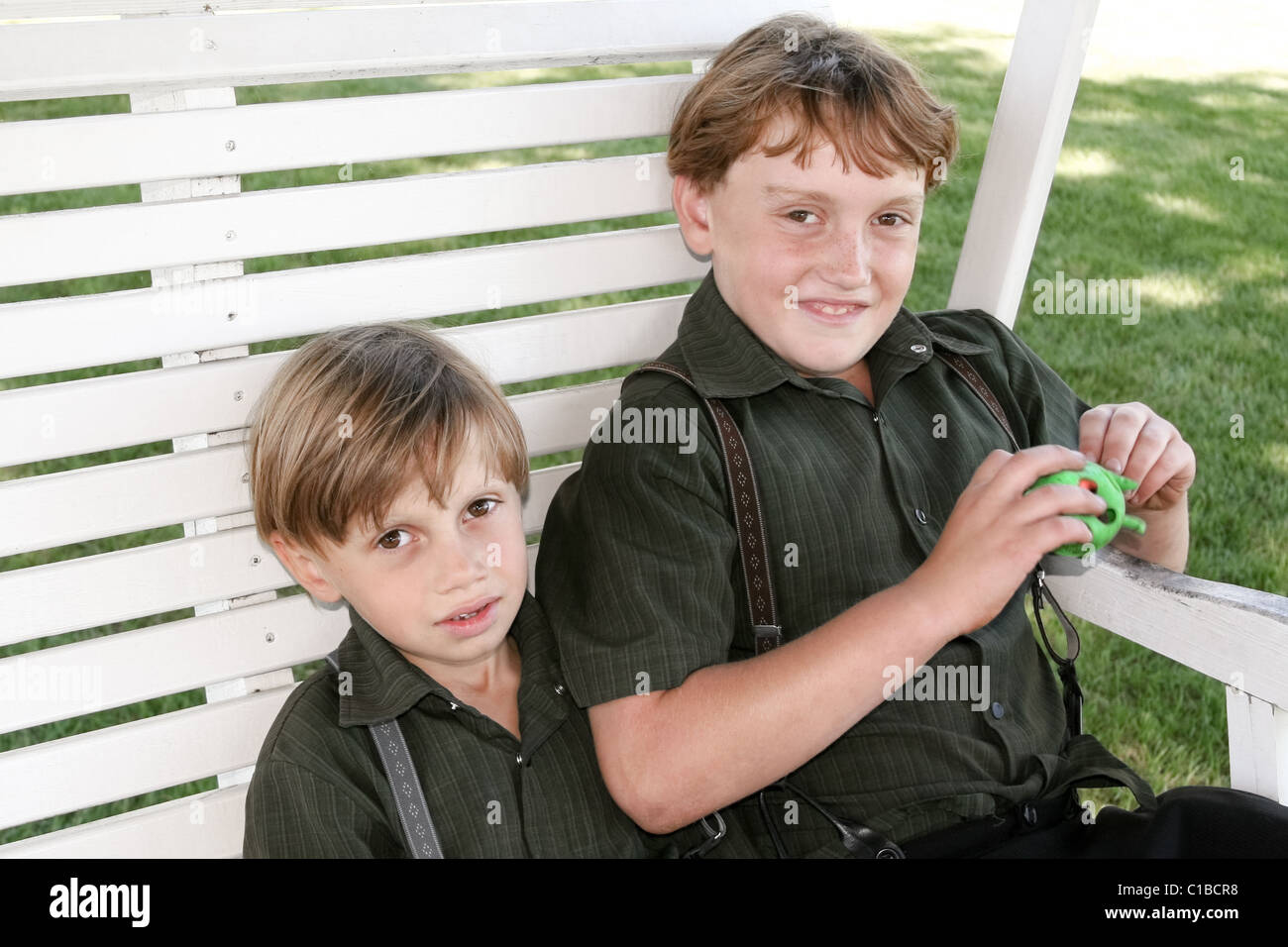 Zwei lächelnde Amish Jungs sitzen in der Bank in Lancaster County, PA USA Stockfoto