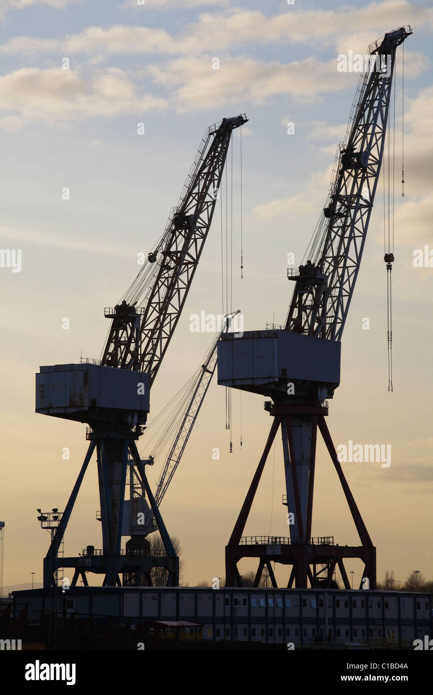 Werftkrane in BAE Systems neben den River Clyde in der Abenddämmerung in Govan, Glasgow, Schottland, Großbritannien Stockfoto