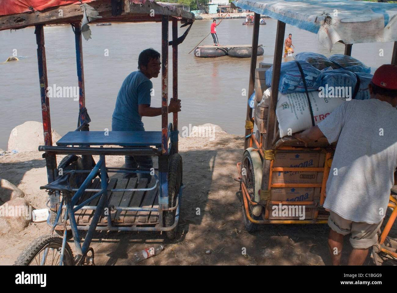 Fahrrad taxis warten auf Kunden und illegal importierte Waren aus Mexiko in Tecun Uman, Guatemala auf den Suchiate-Fluss. Stockfoto