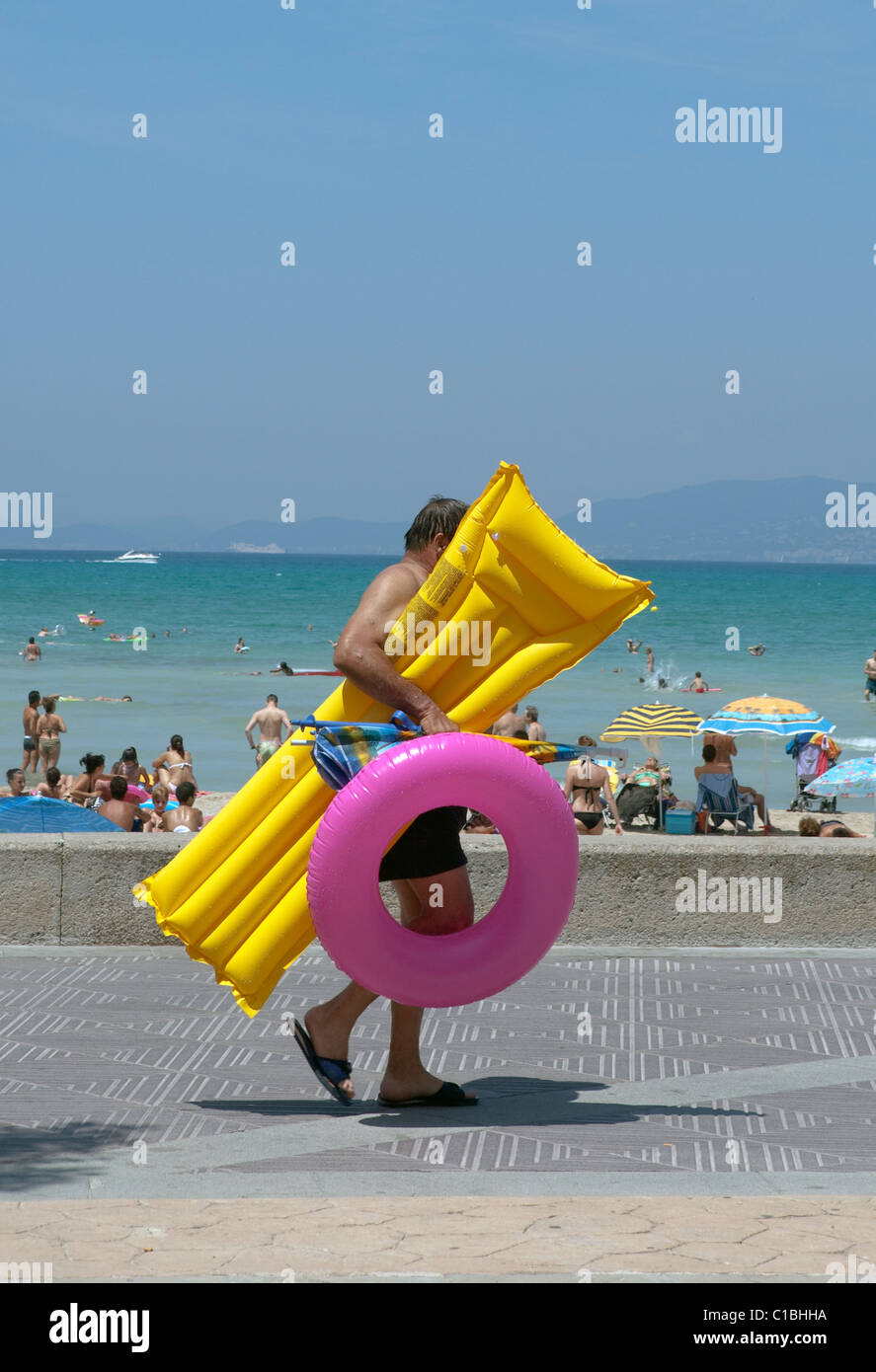 Person zu Fuß direkt am Meer mit Luftmatratze und aufblasbaren Ring bunt,  an der Playa de Palma. Mallorca-Mallorca-Balearen-Spanien Stockfotografie -  Alamy