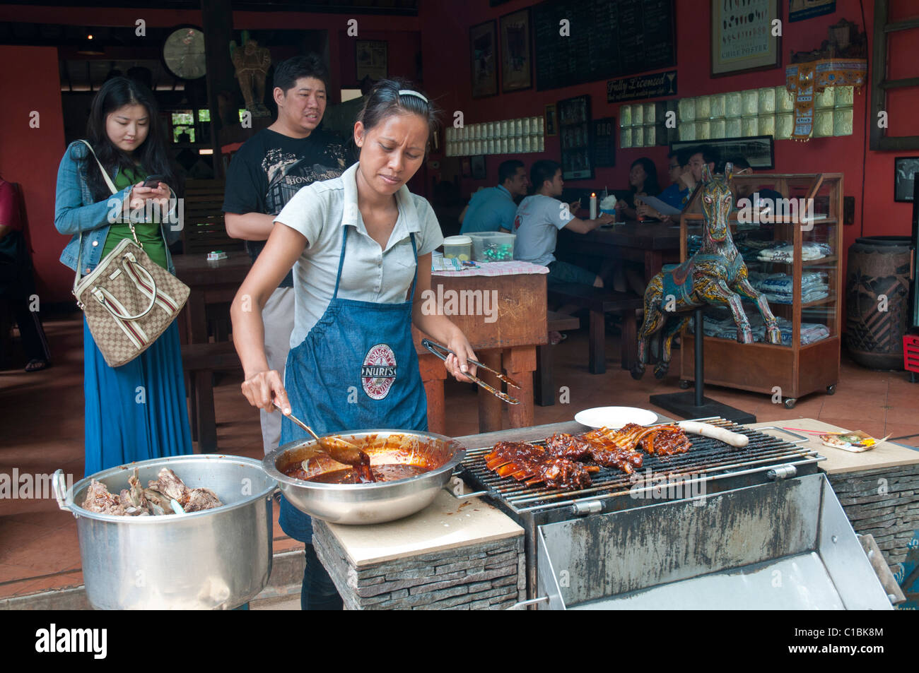 Frau Grillen Schweinefleisch Spareribs über Holzkohle in Ubud, Bali-Indonesien Stockfoto