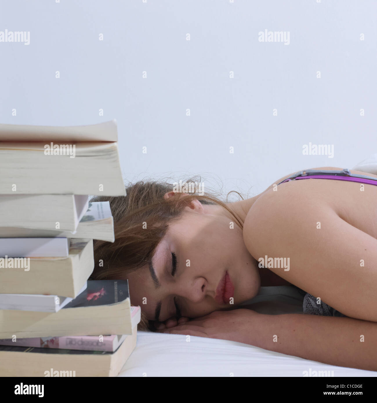 Junge Frau schläft neben Bücher Stockfoto