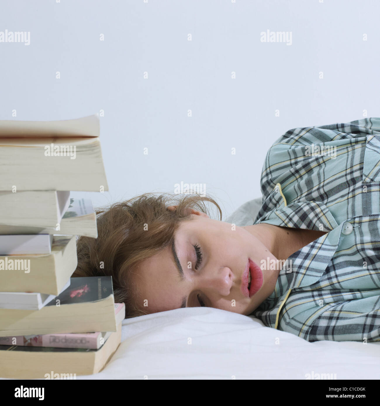 Junge Frau schläft neben Bücher Stockfoto