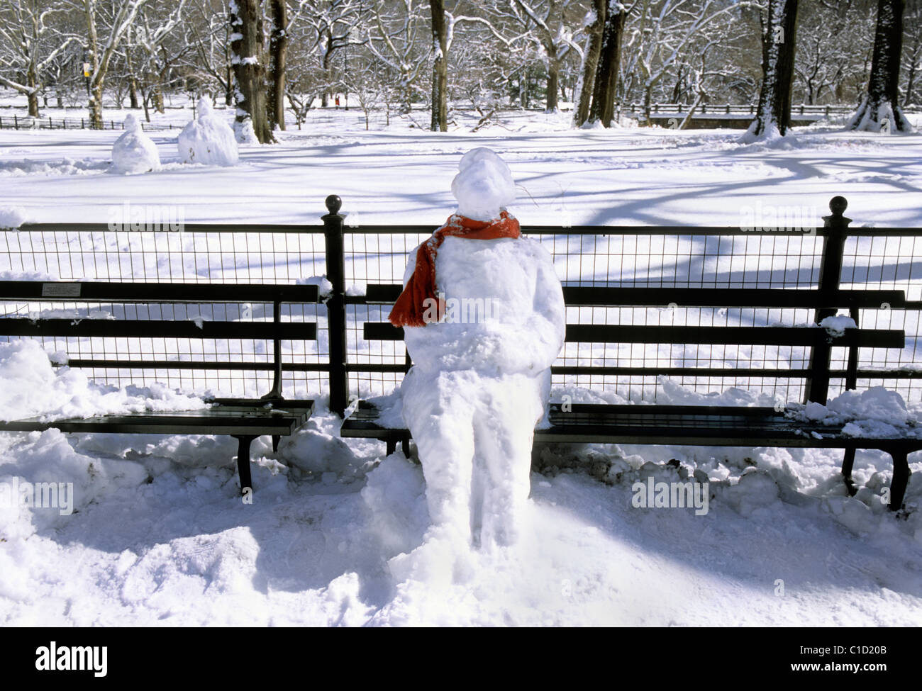 New York, Central Park Snow. Sitzender gefrorener Schneemann mit rotem Schal, der allein auf einer Parkbank sitzt. Keine Menschen Stockfoto