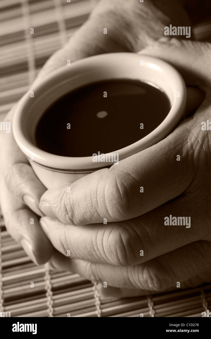 die Hände umarmen eine Tasse schwarzen Kaffee Stockfoto