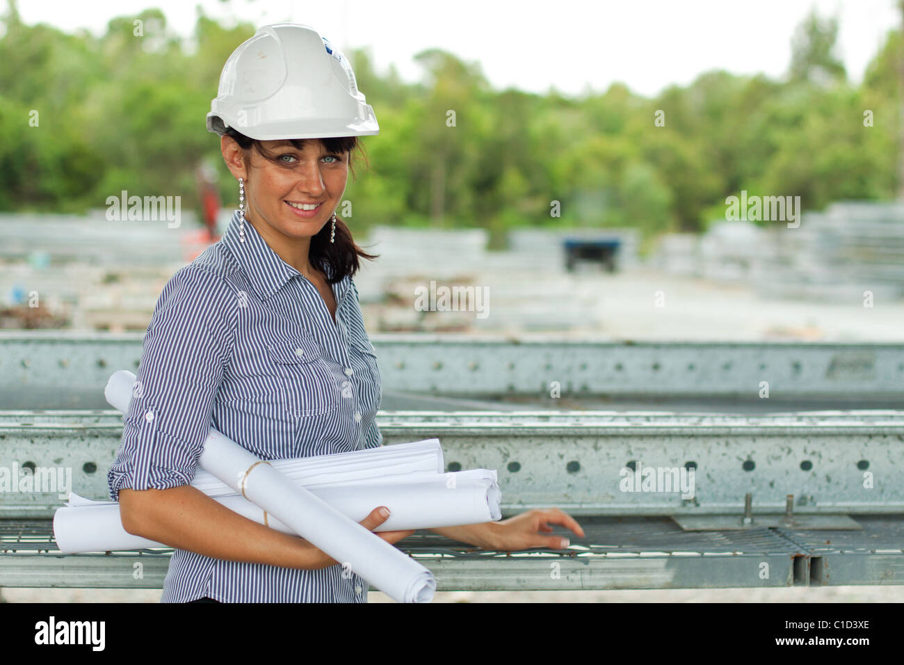 Junge Ingenieurin Frau mit gerollten Zeichnungen im Lager Stockfoto