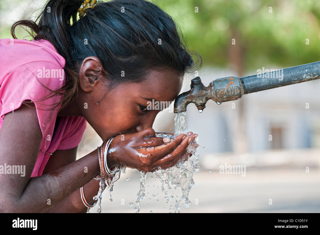 Junge schlechte niedrigere Kaste Inderin aus einem Wasserhahn zu trinken. Andhra Pradesh, Indien Stockfoto