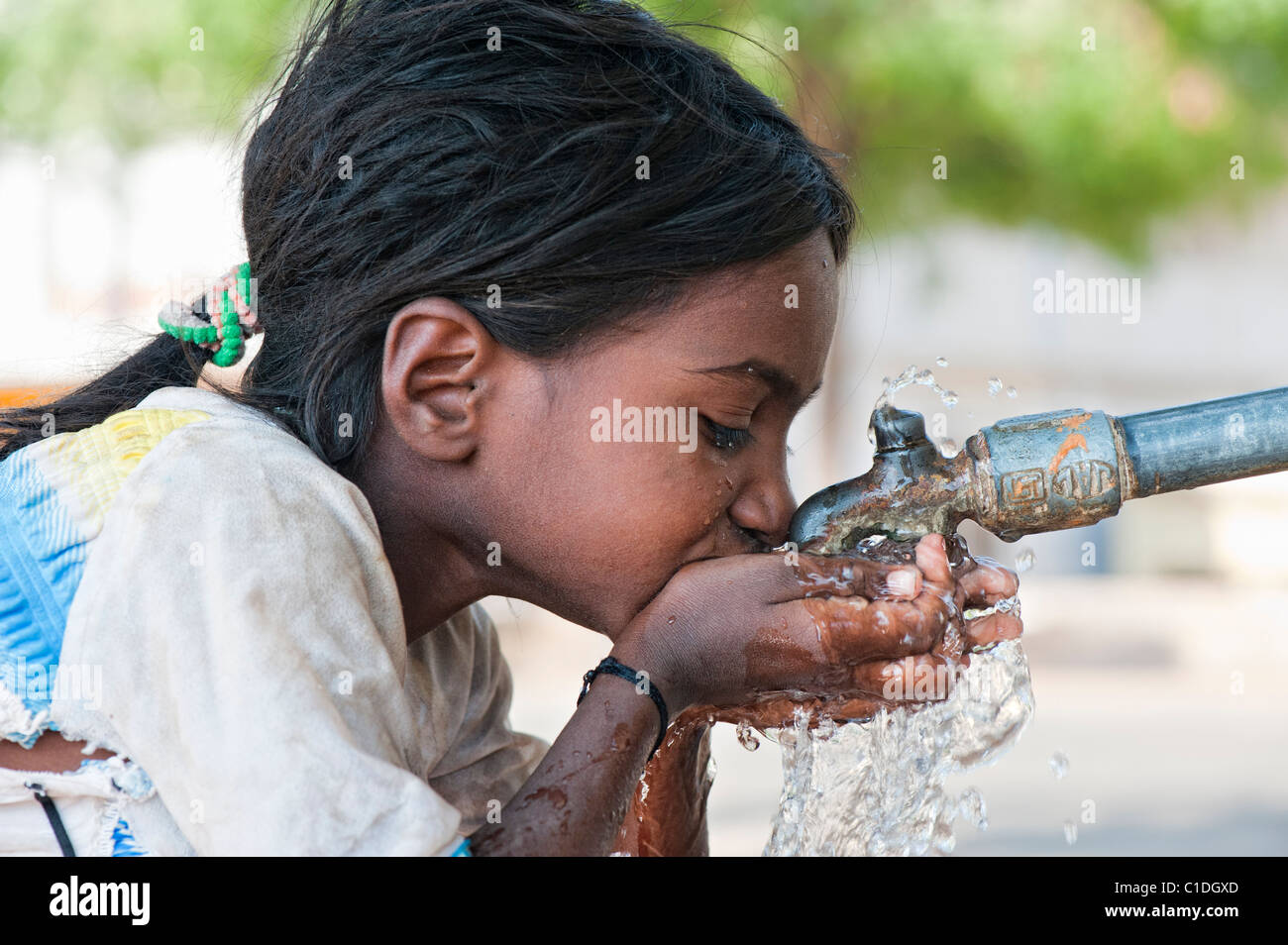 Junge schlechte niedrigere Kaste Inderin aus einem Wasserhahn zu trinken. Andhra Pradesh, Indien Stockfoto