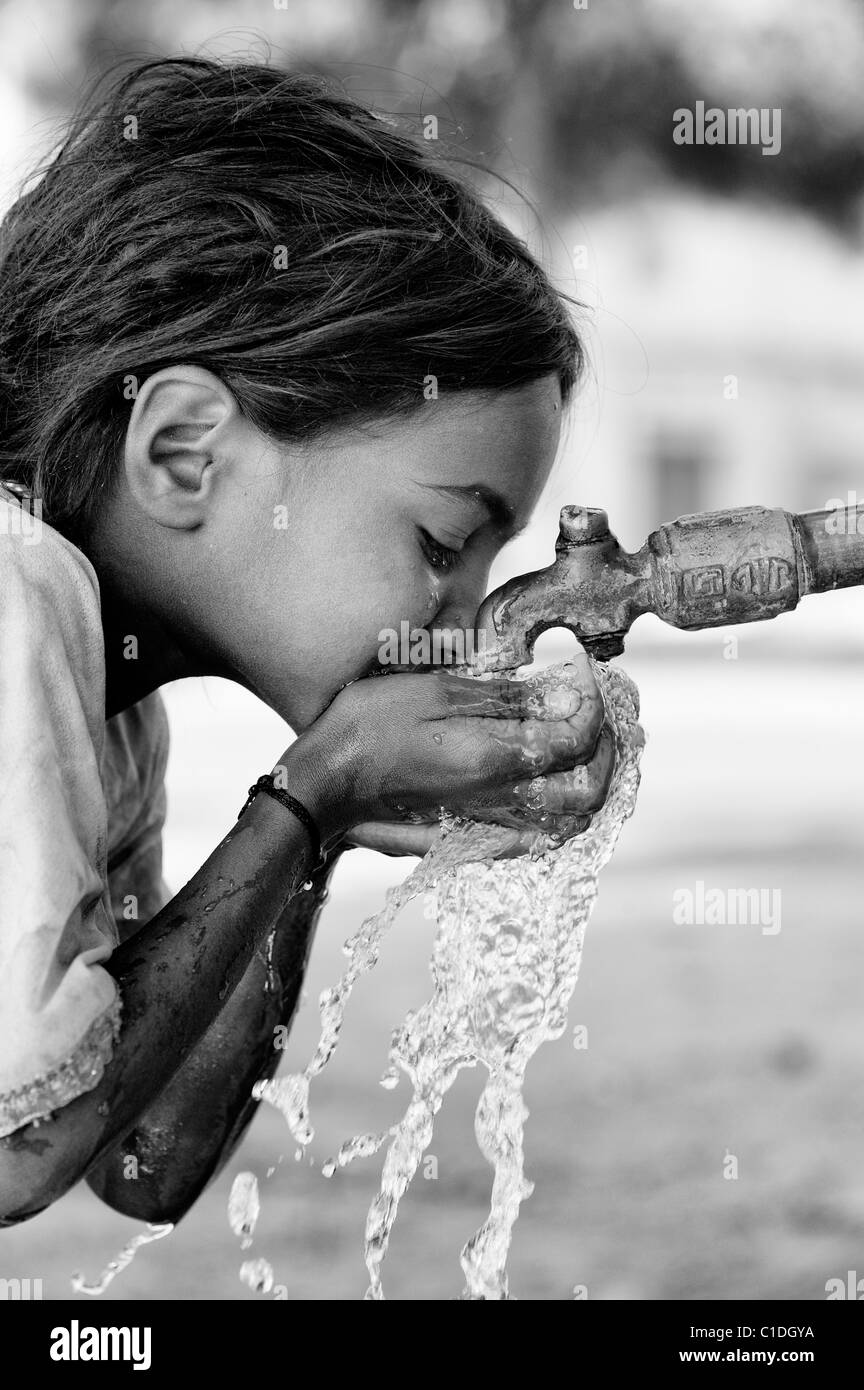Junge schlechte niedrigere Kaste Inderin aus einem Wasserhahn zu trinken. Andhra Pradesh, Indien. Schwarz / weiß Stockfoto