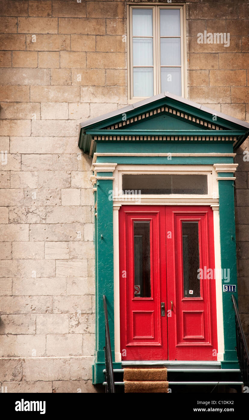 Eine kühne rote Tür, umrahmt von einer alten Steinmauer in Old Montreal, Quebec. Stockfoto