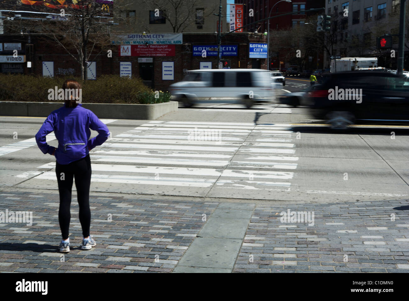 Ein Jogger/Läufer wartet darauf, überqueren Sie die Straße an einem Fußgängerüberweg in New York City USA Stockfoto