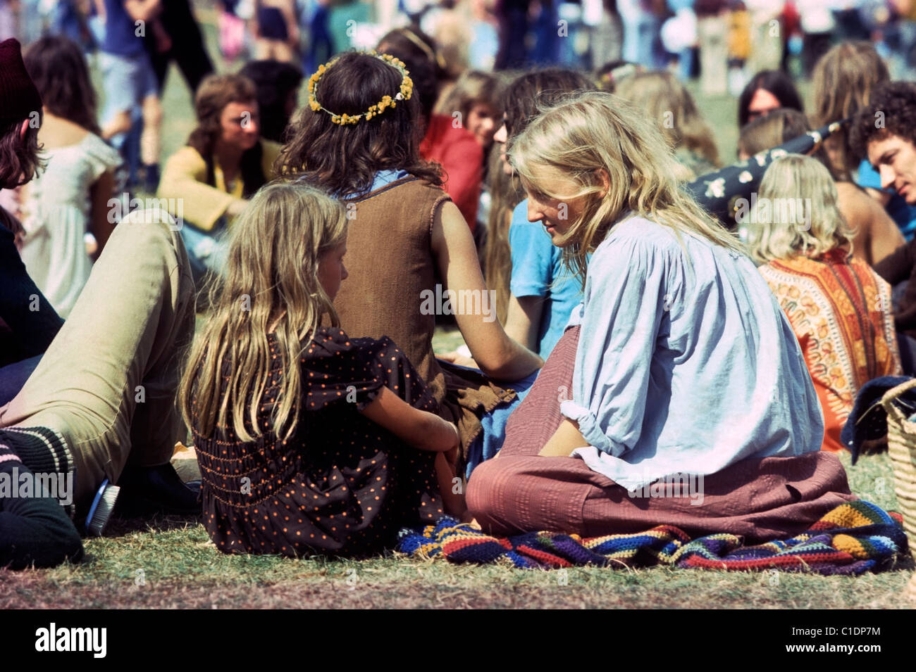 Vintage-Foto von Mutter Frau im Gespräch mit Mädchen (ihre Tochter) in einer Menge von Hippies in der 70er Jahre Mode sitzen in einem Feld auf Barsham Fair Musikfestival Beccles Suffolk England 1970er Jahre KATHY DEWITT Stockfoto
