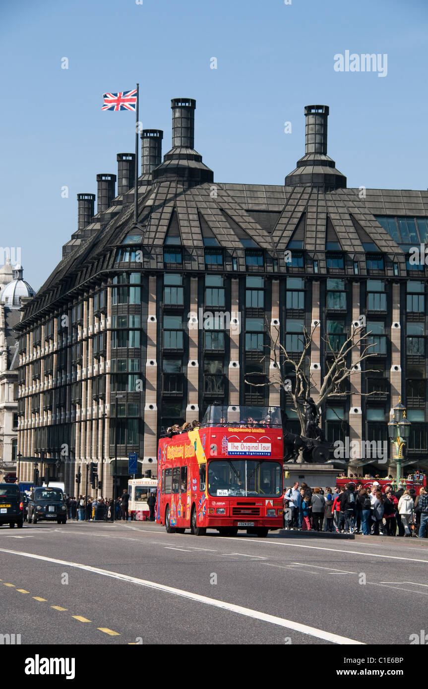 Ein London Tourbus fährt eine Gruppe von Touristen auf Westminster Bridge. Der Union Jack Flagge Dateien oben Portcullis House. Stockfoto