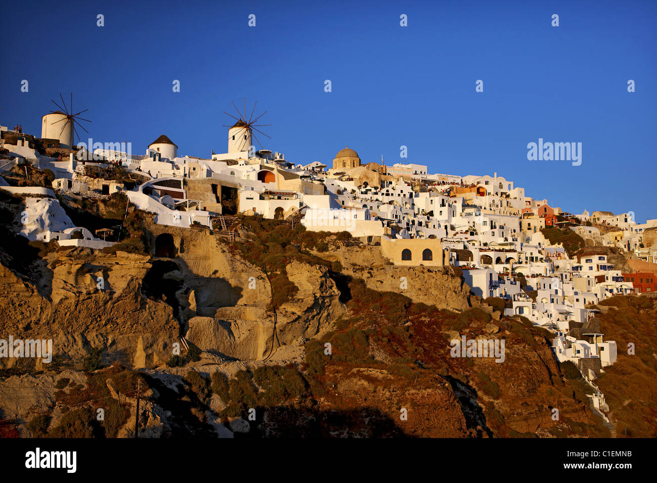Blick auf den östlichen Teil des Dorf Oia mit seiner berühmten Windmühlen bei Sonnenuntergang. Santorin, Kykladen, Griechenland Stockfoto