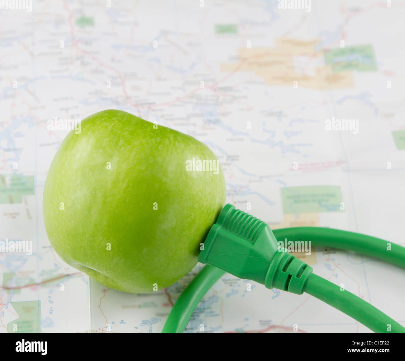 Grüner Apfel mit grünen elektrischen Stecker befindet sich auf einer unscharfen Fokus-Karte in einem Bild des morgigen grüne Energieinnovation Stockfoto