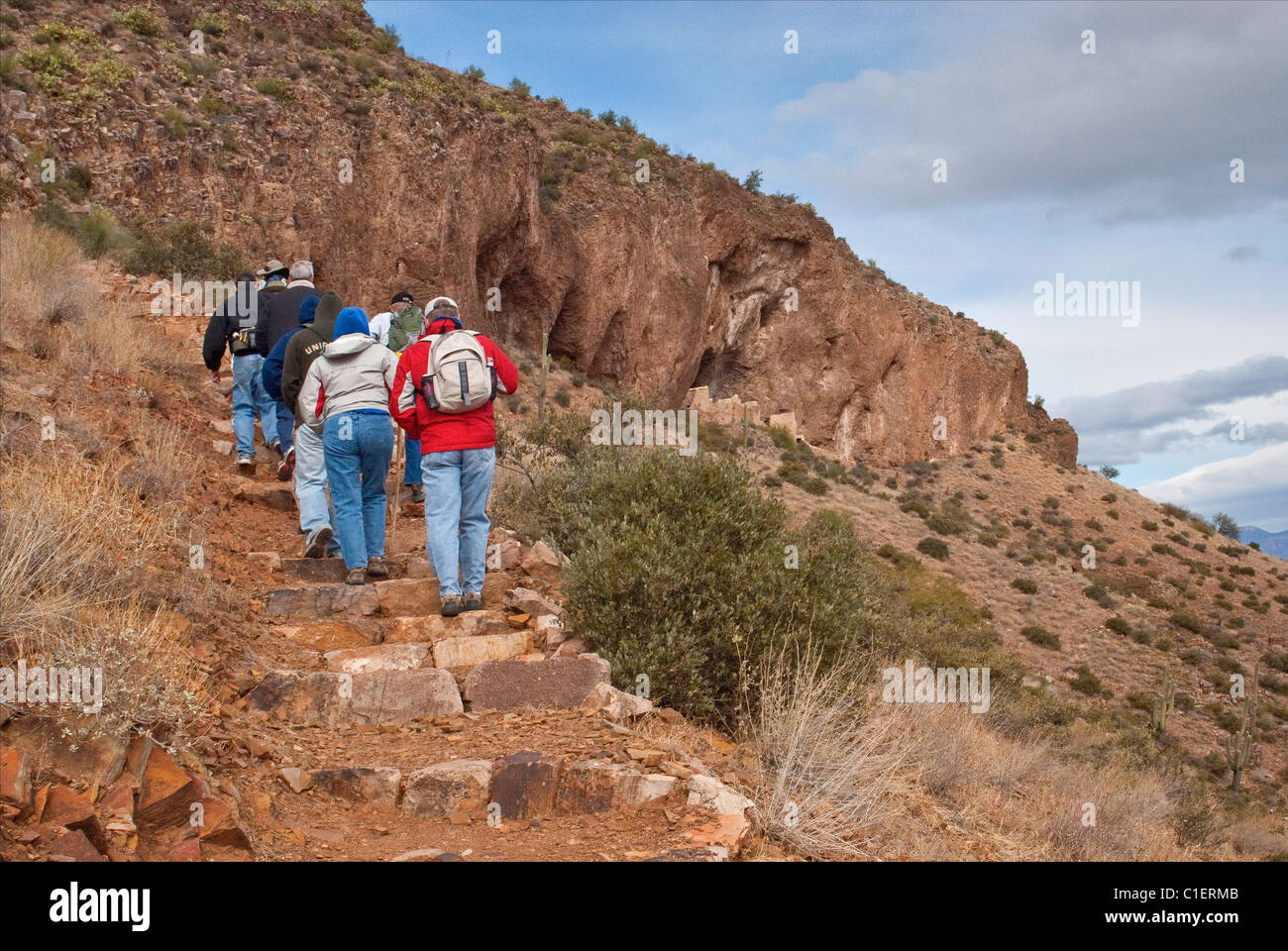 Besucher wandern zum Upper Cliff Dwelling am Tonto National Monument, Superstition Mountains, Arizona, USA Stockfoto