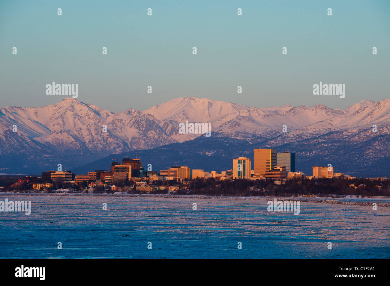 DIE CHUGACH MOUNTAINS STEHEN HINTER DER SKYLINE VON ANCHORAGE IN DER ABENDDÄMMERUNG Stockfoto
