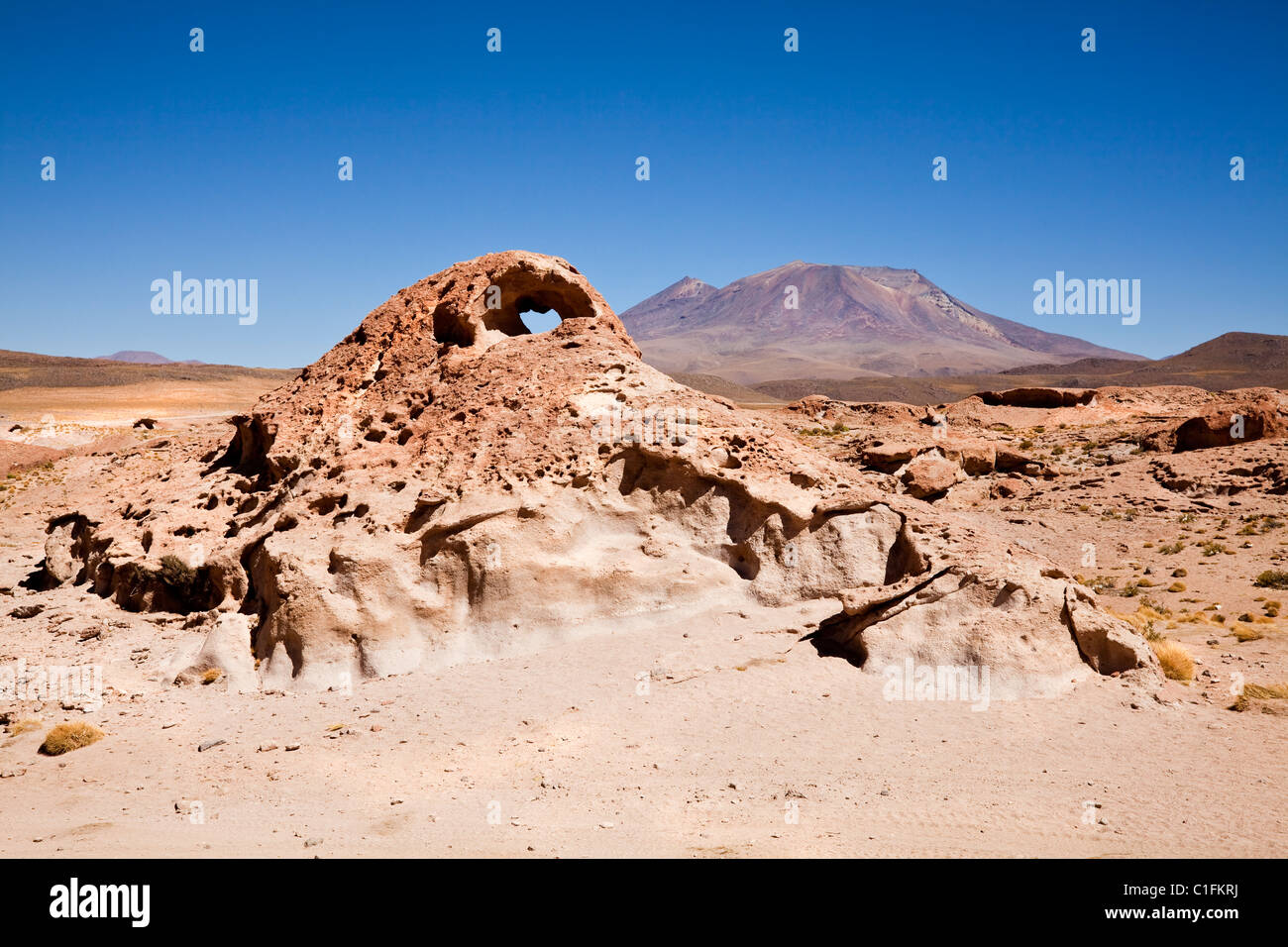 Wüste Landschaftsansicht mit Felsbogen und Vulkan im Hintergrund, South Western Bolivien, Südamerika. Stockfoto