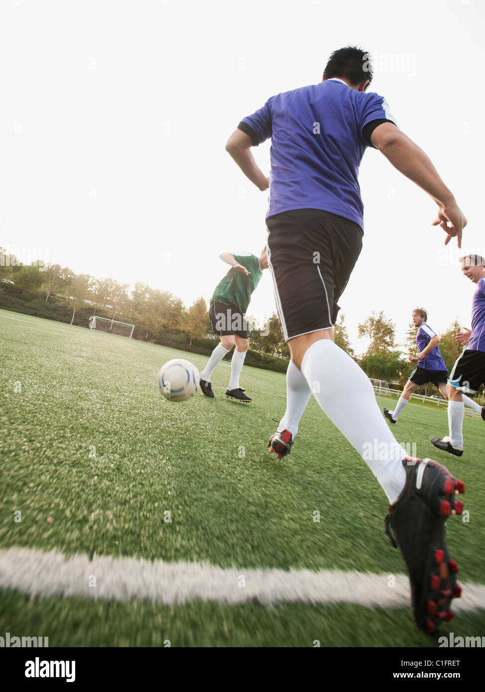 Männer spielen Fußball auf Fußballplatz Stockfoto