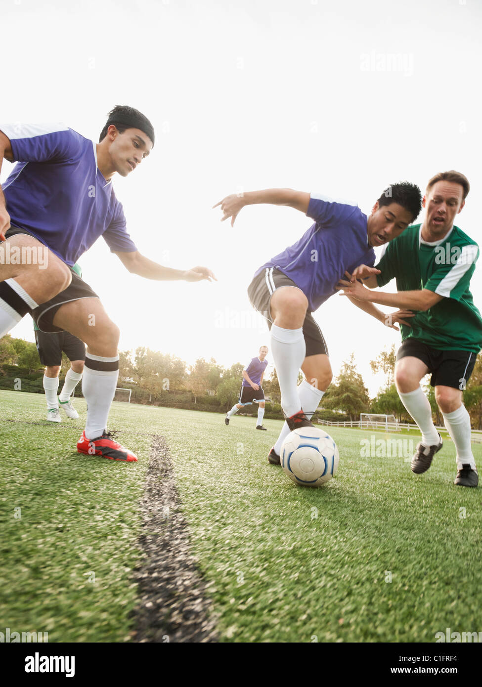 Männer spielen Fußball auf Fußballplatz Stockfoto