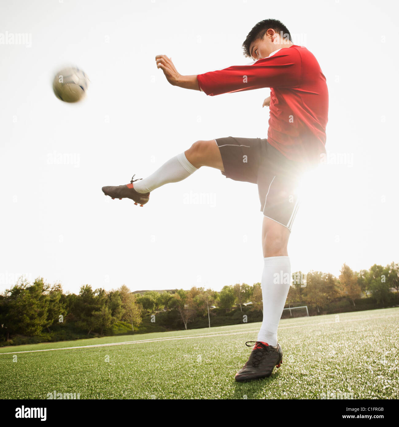 Asiatische Fußball-Spieler treten Ball auf Fußballplatz Stockfoto