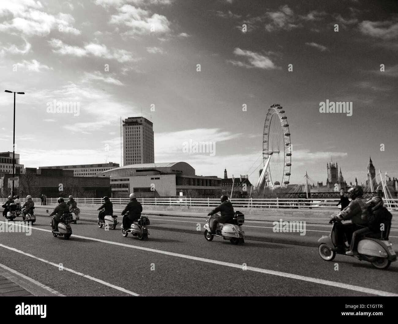 Vespas und Lambrettas fahren über Waterloo Bridge mit dem London Eye im Hintergrund Stockfoto