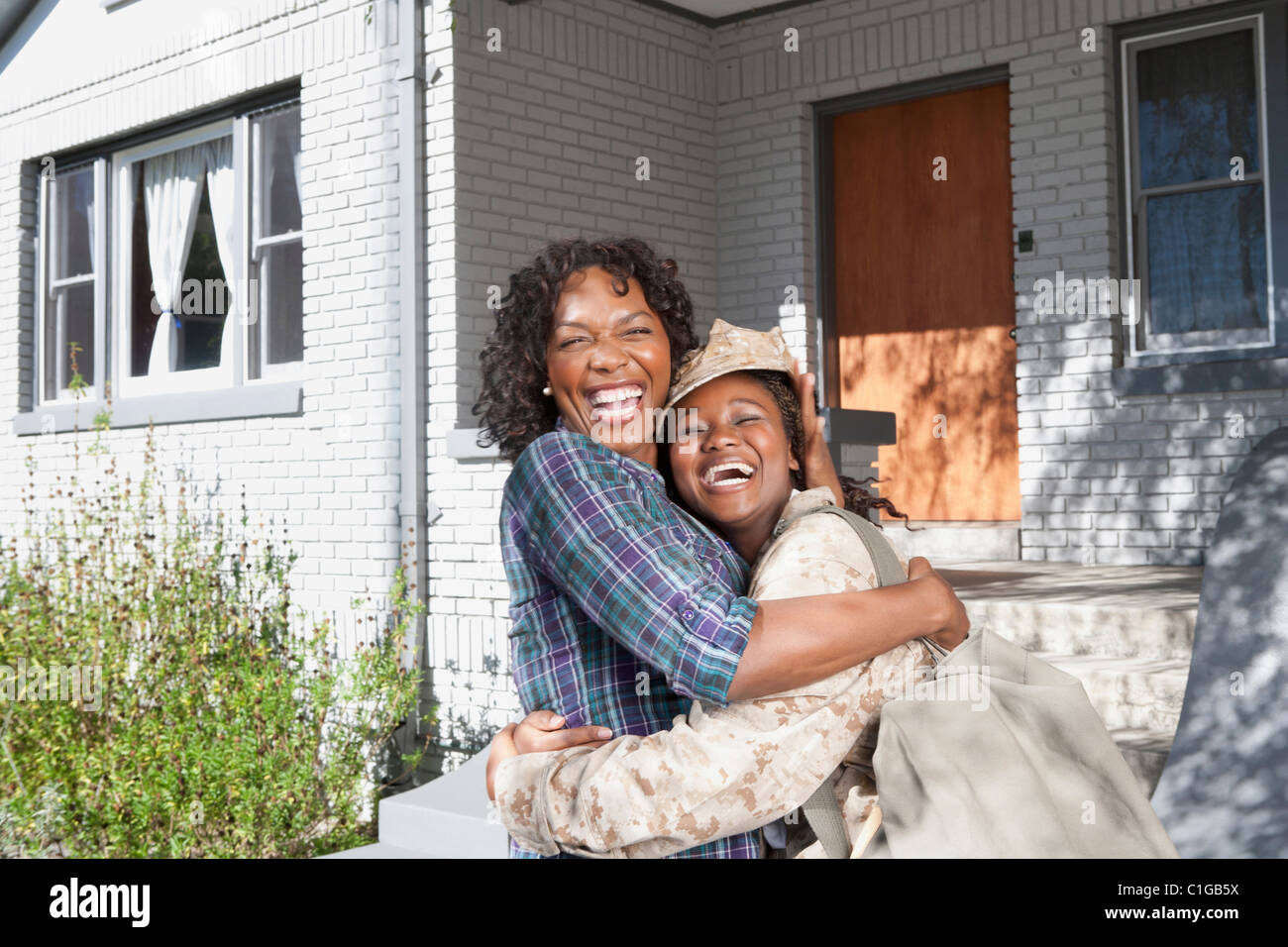 Schwarze Mutter umarmt Soldat Tochter Stockfoto