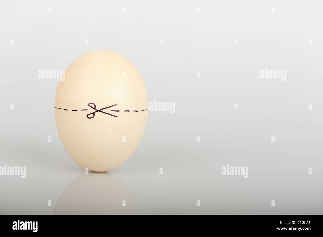 Stock Foto eines Eies mit einer gepunkteten Linie um ihn herum und Schere eine sehr offensichtliche Schnitte hier Erklärung angibt. Stockfoto