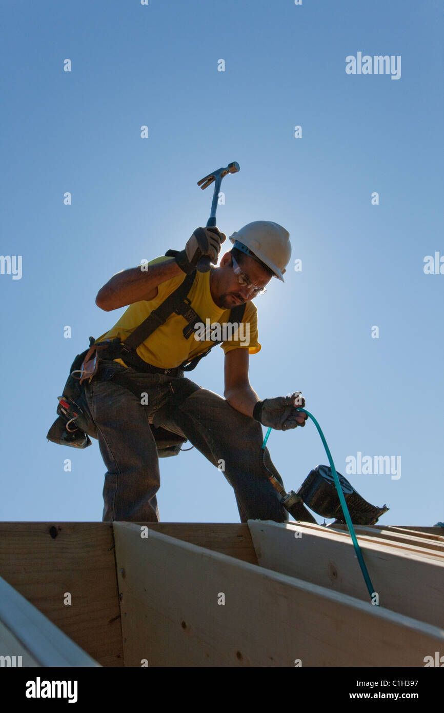 Hispanische Zimmermann mit einem Hammer auf die Sparren auf Dach in einem Haus im Bau Stockfoto