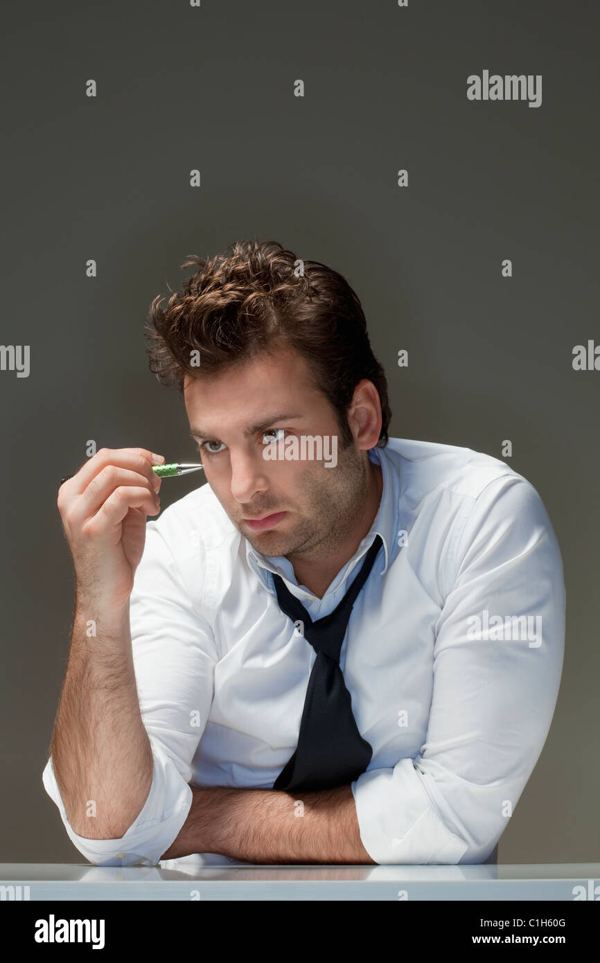 Geschäftsmann in weißen Hemd Blick auf Stift - isoliert auf grau Stockfoto