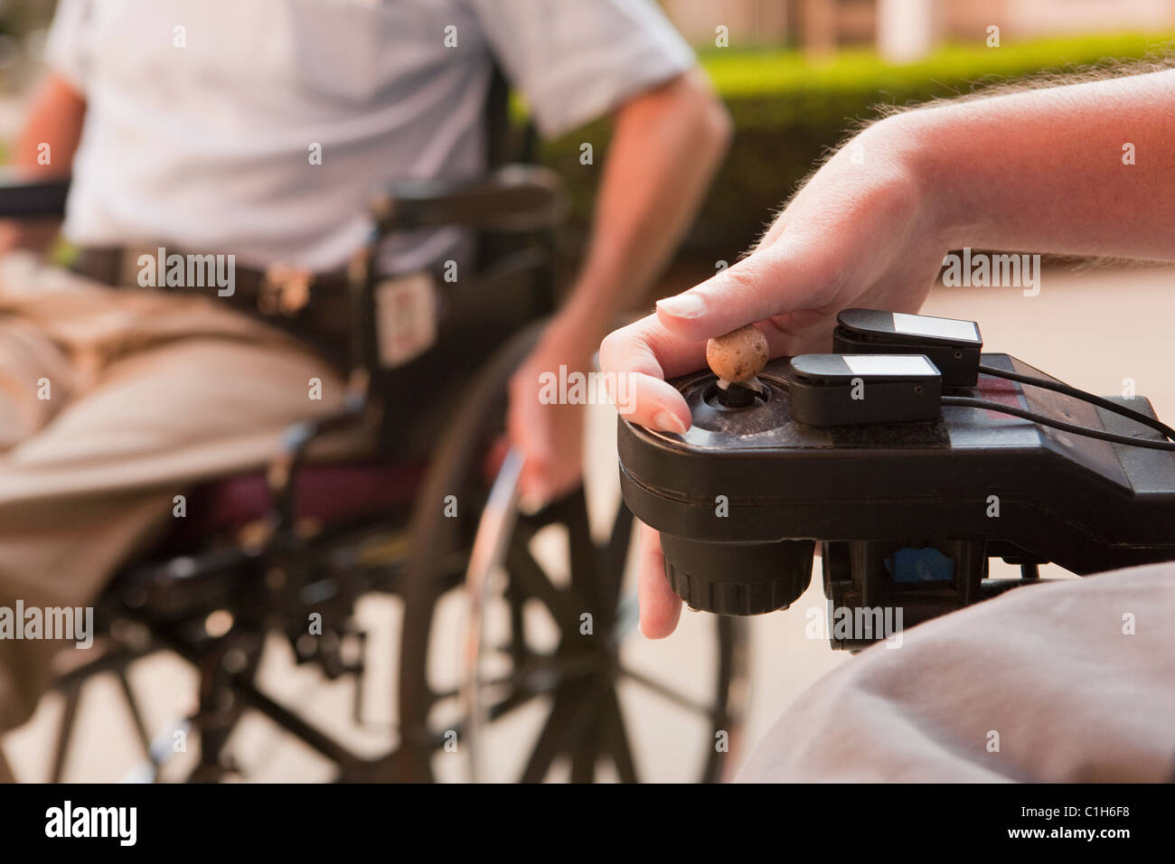 Mann mit Duchenne-Muskeldystrophie, die Steuerung eines motorisierten Rollstuhls mit degenerierten Händen Stockfoto